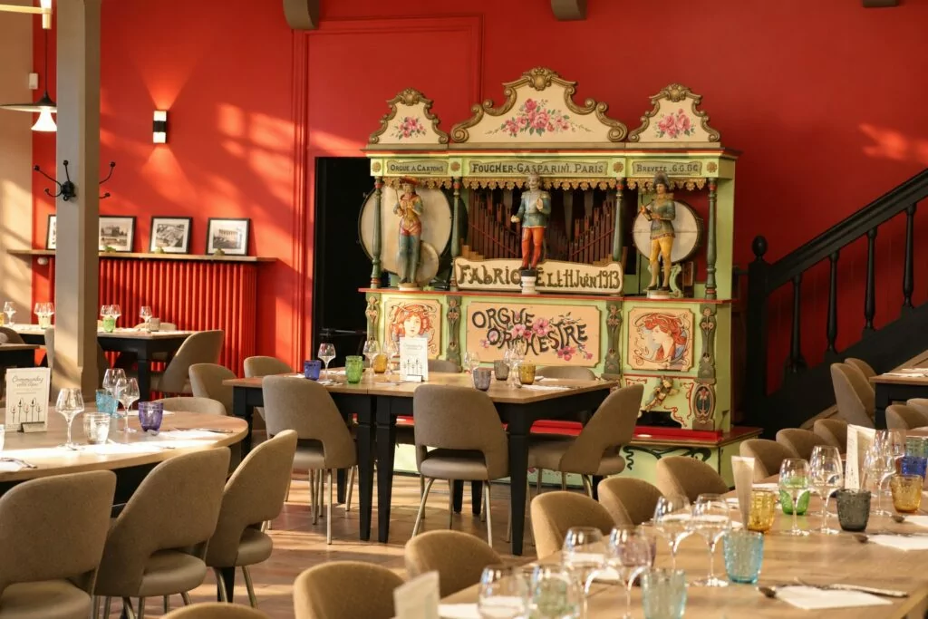 L'Orgue & le Comptoir : l'orgue à cartons Foucher-Gasparini de 1913 devant un mur rouge, entouré de tables dressées